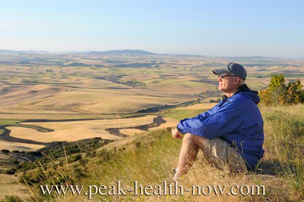 Mens health - hiker sitting on hill enjoying the view.